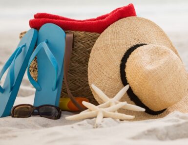 Sac de plage, tongue et chapeau posés sur le sable